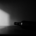 Schwarzweißfotografie einer unscharfen Flasche im harten Licht, als Symbol für den stillen Moment, in dem eine Alkoholabhängigkeit in der Beziehung erkennbar wird.